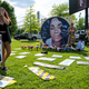 Protesters and volunteers prepare a Breonna Taylor art installation by laying posters and flowers before the “Praise in the Park” event at the Big Four Lawn on June 5, 2021 in Louisville, Kentucky.